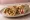 Shish Taouk ma' Batata (شيش طاووق مع بطاطا): an illustration of chicken, potato, garlic sauce, garlic and more on pita.