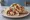 Shish Taouk ma' Toum (شيش طاووق مع توم): an illustration of chicken, garlic sauce, garlic, lemon and more on pita.