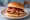 Smoked Turkey Sandwich: an illustration of turkey, bbq sauce, cranberry sauce and pickle on burger bun.