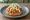 Sope de Tinga: an illustration of chicken, tomato, onion, sour cream and more on tortilla.