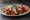 Soslu Döner: an illustration of beef, marinara, tzatziki, tomato and more on bread.