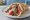 Souvlaki Arni se Pita: an illustration of lamb, tzatziki, tomato, onion and more on pita.