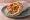 Souvlaki Kotopoulo se Pita: an illustration of chicken, tzatziki, tomato, onion and more on pita.
