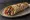 Sucuk Dürüm: an illustration of sucuk, beef, tomato, onion and more on pita.