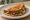 Taco con Costra de Queso: an illustration of queso oaxaca, beef, onion, cilantro and more on tortilla.