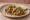 Taco de Carnitas: an illustration of pork, onion, cilantro, lime and more on tortilla.