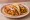 Taco de Mukbil Pollo: an illustration of chicken, pork and onion on tortilla.