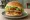 Tavuk Burger: an illustration of chicken, lettuce, tomato, onion and more on burger bun.