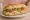 Tavuklu Sandviç: an illustration of chicken, lettuce, tomato, mayonnaise and more on bread.