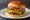 Tillamook Cheddar Burger: an illustration of beef, cheddar cheese, lettuce, tomato and more on burger bun.
