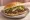 Torta de Barbacoa: an illustration of beef, refried beans, avocado, onion and more on bread.