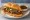 Torta de Birria: an illustration of beef, refried beans, onion and cilantro on bread.