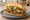 Torta de Bistec Encebollado: an illustration of beef, onion, refried beans, avocado and more on bread.