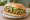 Torta de Chicharrón en Salsa Verde: an illustration of refried beans, avocado, onion and cilantro on bread.
