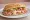 Torta de Jamón con Queso: an illustration of ham, refried beans, avocado, tomato and more on bread.