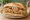 Torta de Migas: an illustration of egg, tortilla, refried beans, salsa and more on bread.