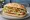 Torta de Milanesa de Pollo: an illustration of chicken, egg, refried beans, avocado and more on bread.