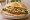 Torta de Milanesa de Res: an illustration of beef, egg, refried beans, avocado and more on bread.
