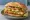 Torta de Pescado: an illustration of fish, refried beans, avocado, lettuce and more on bread.