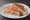 Tostado con Tomate: an illustration of ham, cheese and tomato on white bread.