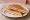 Tostado de Jamón y Queso: an illustration of ham and cheese on white bread.