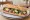 Tuna Niçoise Sandwich: an illustration of tuna, egg, olives, tomato and more on baguette.