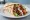 Vegan Gyros: an illustration of mock meat, tomato, onion and lettuce on pita.