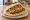 Vegan Schnitzel (שניצל טבעוני): an illustration of mock meat, tahini, lettuce, tomato and more on pita.