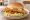 Walleye Sandwich: an illustration of lettuce, tomato and tartar sauce on burger bun.