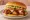 Whataburger Honey BBQ Chicken Strip Sandwich: an illustration of chicken, bbq sauce, lettuce and tomato on burger bun.