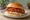 Yangnyeom Chicken Sandwich: an illustration of chicken, gochujang, garlic, ginger and more on burger bun.