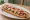 Zapiekanka Krakowska: an illustration of cheese, onion, ketchup and garlic sauce.