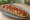 Zapiekanka z Boczkiem: an illustration of bacon, mushroom, cheese, onion and more.
