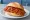 Zigeunerschnitzel Brötchen: an illustration of pork, bell pepper, onion, tomato and more on kaiser roll.